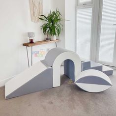 a white and grey slide in the corner of a room with a potted plant