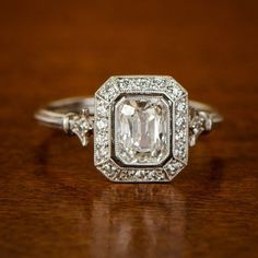 an engagement ring with a large diamond surrounded by smaller diamonds on a wooden table top