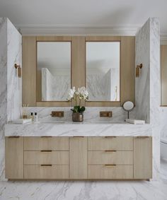 a large bathroom with marble counter tops and wooden cabinets, along with two mirrors on the wall