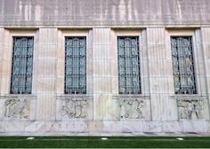 three windows on the side of a building with green grass in front of it and an american flag