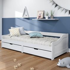 a white daybed with drawers underneath it in a blue and white room next to wooden flooring