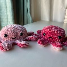 two crocheted stuffed animals sitting on top of a white table next to each other