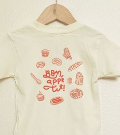 Handmade and designed kids' shirt with love by two mamas. Celebrate the joy of baking with our handmade kids' shirt, featuring a delightful bakery illustration! Adorned with a baguette, croissant, pretzel, doughnut, and adorable bakery accessories, plus a cute puffed bakery icon, this shirt adds a sprinkle of sweetness to any outfit. Perfect for little ones who love all things bakery! Bonus! get the Cute Bakery Sticker: a delightful peel-and-stick addition that transforms your picnic background Cute Organic Cotton T-shirt For Everyday, Bakery Merch, Bakery Accessories, Picnic Background, Bakery Illustration, Bakery Icon, Cute Bakery, Toddler Baby Boy, Heat Press Designs