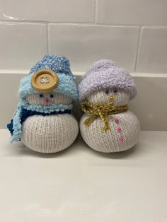 two knitted snowmen sitting next to each other on top of a white counter