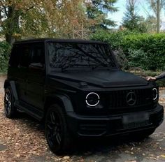 a man standing next to a black mercedes g class