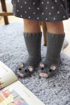 the legs of a child wearing knitted socks and slippers with pink dots on them