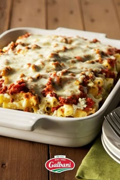 a casserole dish with meat and cheese in it sitting on a wooden table