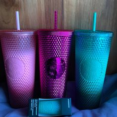 three different colored starbucks cups next to each other