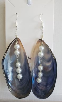 a pair of earrings with pearls hanging from them