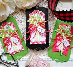 three tags with bows and ribbons on them sitting next to some scissors, yarn and flowers