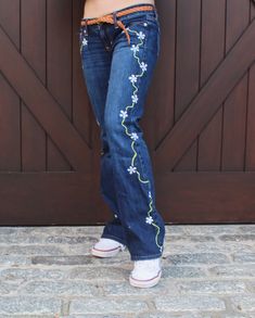 American Eagle favorite boyfriend stretch jeans in dark wash. White floral detailing and light green vine chain are reminiscent of the grooovy 70's!  Giggle Denim is a hand-painted denim brand, which utilizes gently-used denim and revamps them with unique designs to go against fast fashion. 50% of all earnings are donated to Susan G. Komen for the Cure Breast Cancer Foundation and WIN Women in Need. Care Instructions: We recommend you wash these jeans with cold water on a delicate setting on you Senior Painted Jeans, Hand Painted Jeans, Daisy Chains, Susan G Komen, Feminine Top, Painted Jeans, Vintage Levis Jeans, Denim Diy, Painted Denim