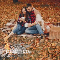 a man and woman sitting next to each other on a blanket near a campfire