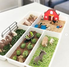 four trays filled with different types of farm animals and plants on top of a table