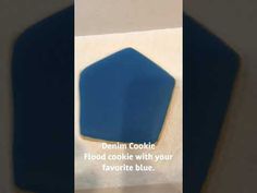 a blue cookie sitting on top of a piece of paper next to a white wall