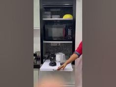 a man standing in front of a microwave oven next to a toaster on top of a counter