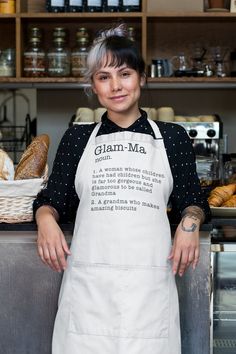 a woman wearing an apron standing in front of some bread