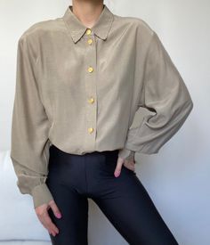 A beautiful neutral shirt with gold buttons and removable shoulder pads.  Looks great worn as a shirt or a tunic, depending on your height. Mint condition. Composition: cupro , viscose Size : S-XL depending on the desired drape. Our model is size XS/S and the shirt is not pinned on her. Note: If you have any additional questions about the sizing and measurements of the items, please DM me! *all items have been professionally cleaned and ready to wear! Most of the items are vintage and therefore Gold Long Sleeve Tops With Button Cuffs, Chic Collared Gold Shirt, Chic Gold Collared Shirt, Gold Collared Blouse For Work, Classic Brown Blouse With Button Cuffs, Gold Collared Shirt For Work, Classic Gold Blouse For Workwear, Gold Formal Blouse With Button Closure, Gold Blouse With Button Closure For Formal Occasions