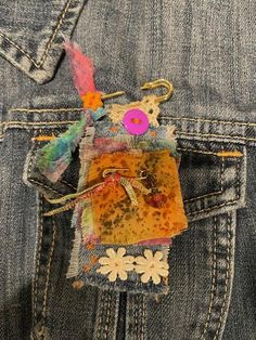 the back pocket of someone's jean jacket with an embroidered patch and button on it