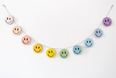 a string of smiley face magnets hanging from a line on a white wall,