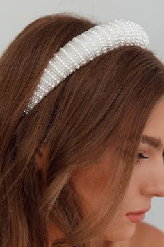 a woman wearing a headband with pearls on it