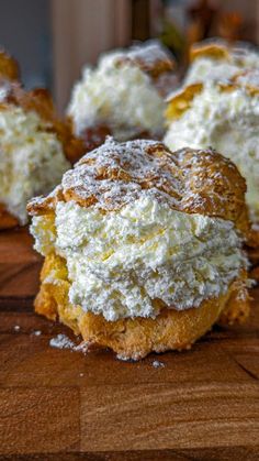 the pastry is covered with powdered sugar and sits on a wooden table next to other pastries