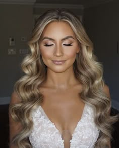 a woman with long blonde hair wearing a wedding dress and makeup is looking at the camera