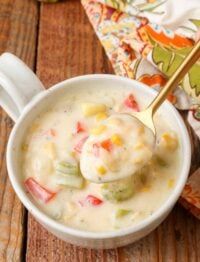 a white bowl filled with soup on top of a wooden table next to a spoon