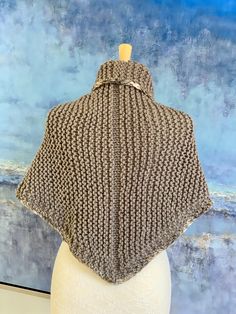 a white mannequin head wearing a gray knitted ponchy