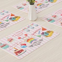 four placemats with designs on them sitting on a wooden floor next to a vase filled with flowers