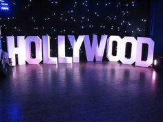 the word hollywood is lit up in front of a stage with lights and stars on it