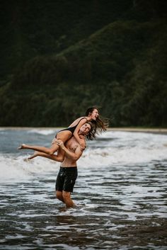 a man and woman are playing in the water at the beach while holding each other