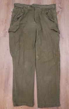 Belgian military trousers These pants have five buttons as a closure. Two open side pockets. A pocket on the right side at the level of the thigh. A pocket on the right buttock. These pants are stitched in several places, it has stains. Size: C52 Height: 47 cm Length: 107 cm Length between legs: 81 cm Feet: 21 cm Weight: 760 grams. Combat Trousers With Belt Loops, Vintage Cargo Style Workwear Bottoms, Vintage Cargo Style Bottoms For Work, Military Style Cargo Pants With Tapered Leg, Combat Style Straight Leg Pants With Pockets, Khaki Combat Bottoms With Belt Loops, Khaki Combat Bottoms With Patch Pockets, Khaki Pants With Flap Pockets, Combat Style Trousers With Belt Loops