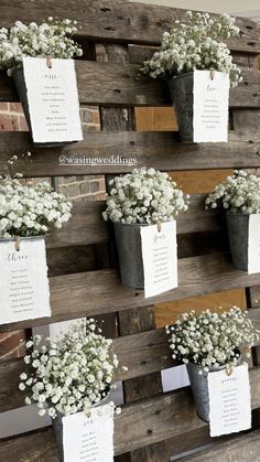 flowers are placed in buckets on a wooden pallet with seating cards attached to them