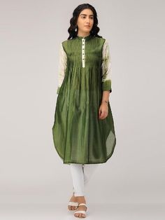 An olive green chanderi pintuck front placket tunic with 3/4th sleeves in shibori. Features: Front placket kurta with 3/4th shibori sleeves Shell - pure cotton silk fabric Pintuck detailing in front with offwhite accents Handmade in India Garment measurements (in Inches): Size XS : Bust-34", Waist-32", Hip-Flared, Shoulder-14", Length-45", Sleeve length-18" Size S : Bust-36", Waist-34", Hip-Flared, Shoulder-14.5", Length-45", Sleeve length-18" Size M : Bust-38", Waist-36", Hip-Flared, Shoulder-1 Spring Handloom Chanderi Kurta, Eid Straight Kurta With Pintucks, Eid Pintucks Straight Kurta, Transitional Long Sleeve Slub Silk Kurta, Traditional Festive Kurta With Pintucks, Festive Traditional Kurta With Pintucks, Bohemian Green Chanderi Kurta, Festive Cotton Silk Kurta With Yoke, Festive Cotton Silk Kurta With Yoke Detail