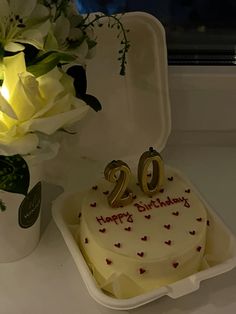 a birthday cake with the number twenty on it and flowers in a vase behind it