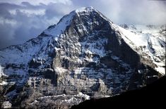 a large snow covered mountain with clouds in the sky over it's top and bottom