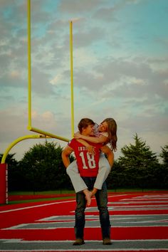 a man holding a woman on top of a football field