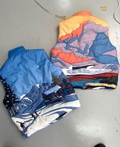 two shirts laying on the floor next to each other, one with an orange and blue shirt