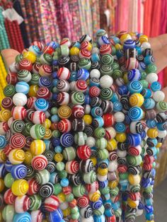 a person holding a bunch of colorful beads in their hand and the bead is multicolored