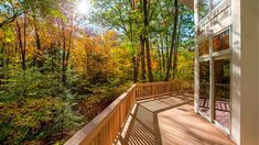 a deck with wooden railings and trees in the background, looking out onto a wooded area