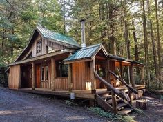 a small cabin in the woods with stairs leading up to it's roof and windows