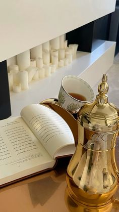 an open book sitting on top of a table next to a tea pot