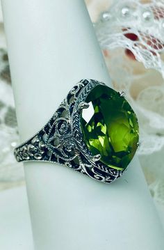 Natural Green Peridot Ring Iris Design#201 Custom Made This is a stunning Art Deco vintage reproduction ring in sterling silver filigree with a 3.12 carat Natural green peridot gemstone. The brilliant natural gem is 13mm in long by 9mm wide. The ring is 17mm North-South on the finger. The inside of the band is marked 925 for solid sterling silver. This is a lovely reproduction of a vintage antique filigree ring. There is beautiful craftsmanship evidenced in the silver filigree setting. See the f Filigree Ring For May Birthstone Gift, May Birthstone Filigree Ring Gift, Green Jewelry With Round Cut Accent Stones, Green Gemstone Filigree Ring For May Birthstone, Green Jewelry With Round Accent Stones, Green Round Jewelry With Accent Stones, Hallmarked Green Gemstones, Green Gemstones With Accent Stones As A Gift, Classic Green Filigree Ring With Gemstone