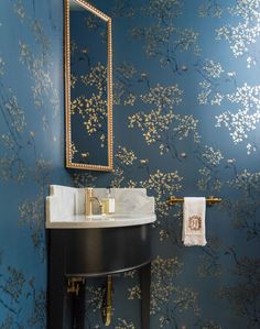 a bathroom with blue and gold wallpaper, a sink and mirror on the wall