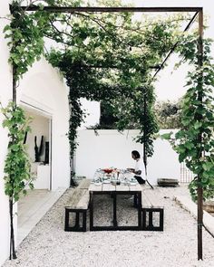 a person sitting at a table under an arbor