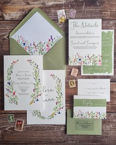 the wedding stationery is laid out on a wooden table with stamps and envelopes