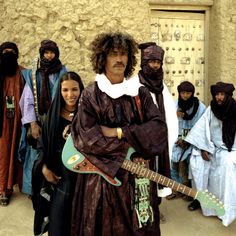 a group of people standing next to each other in front of a building with a guitar