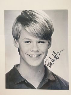 a black and white photo of a young boy with blonde hair wearing a polo shirt