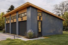 a garage with two windows on the front and side of it, surrounded by green grass