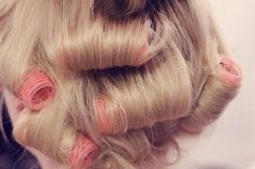 the back of a woman's head with blonde hair and pink pins on it